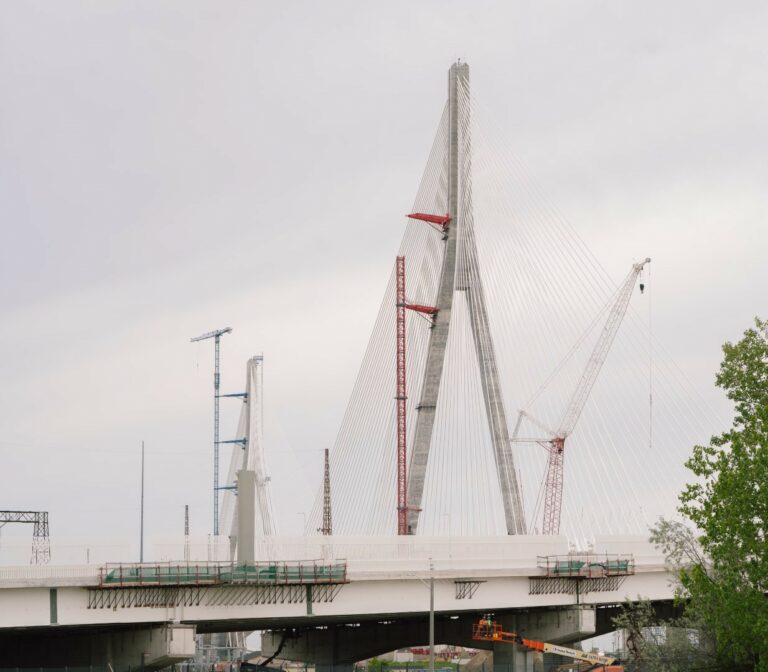Photo of the Gordie Howe Internattional Bridge from a distance showing part of the red crane dismantled for the Canadian tower